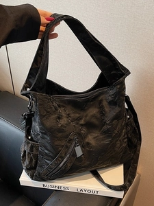Large black tote bag with pleated texture and zipper pocket for urban commuting style