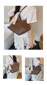 Detail of dark brown hollow-out tote bag with V-shaped opening and letter ribbon