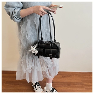 Detail of black glossy crocodile pattern shoulder bag with silver charms and pockets