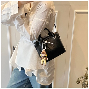 Black leather bucket bag with silver hardware and a cute girl doll charm pendant