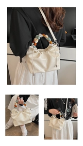 Close-up of cream pleated handbag with marble texture and amber bead handle detail