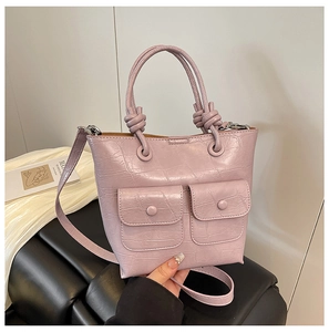 Detail of light purple crocodile embossed tote bag with front pockets and knotted handles