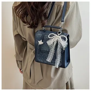 Detail of navy denim crossbody bag featuring pearl bow charm and star rivet accents