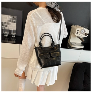 Detail of black crocodile texture bag with double pockets and knotted top handle