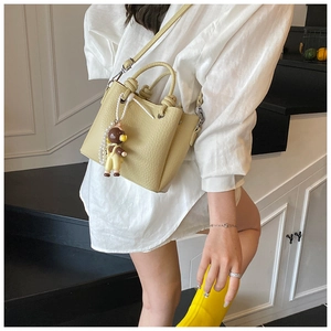 Detail of yellow bucket bag with lychee texture and cute bear pendant on stairs