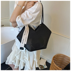 Detail of black laser-cut tote bag featuring chic hollow patterns and lettered ribbon strap