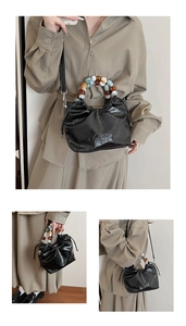 Detail of black glossy patent leather bucket bag with vibrant colorful beaded handle
