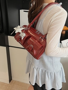 Deep red glossy shoulder bag with dual front pockets and silver star charm detail