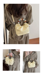 Detail of light yellow bucket bag featuring a colorful resin bead handle and pleated PU leather