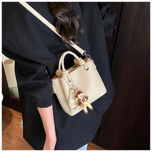 Off-white bucket bag with litchi texture and pearl charm detail worn cross-body