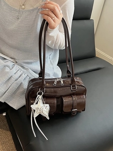 Brown faux leather handbag with crocodile pattern pockets and star pendant on sofa