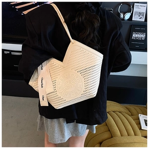 Detail of hollow circular perforated faux leather tote bag with branded canvas strap