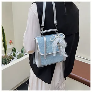 Detail of blue sequin denim handbag with silver star buckle and white lace bow