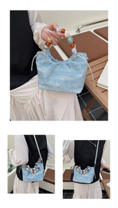 Detail of light blue denim bucket bag with colorful resin bead handle and shoulder strap