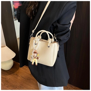 Detail of beige pebble leather bucket bag with decorative knots and fashion printing