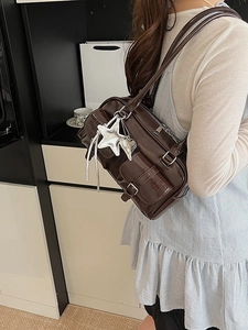 Khaki crocodile pattern shoulder bag with silver star charms worn by a model