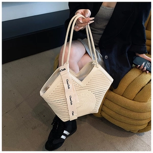 Detail view of beige tote bag with geometric hollow perforations and logo webbing