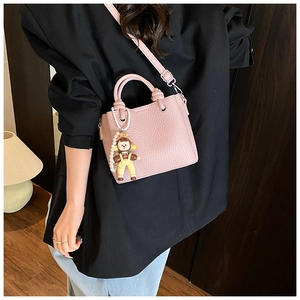 Pale pink leather bucket bag with pearl charm and cute doll worn by model in suit