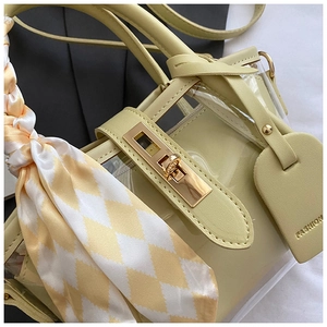 Détail d'un sac en cuir et PVC avec fermoir doré et poignée ornée d'un foulard