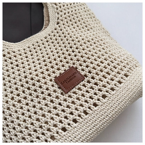 Gros plan du sac de plage en maille beige montrant la texture et le patch en cuir brun