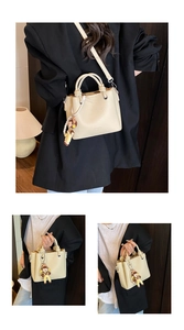 Detalle del bolso beige de cuero granulado con colgante de perlas y asa anudada