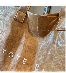 Detail shot of the clear PVC outer layer and tan leather texture tote bag with bold text
