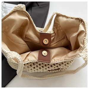Détail intérieur du sac de plage tissé montrant la doublure en satin et la poche zippée