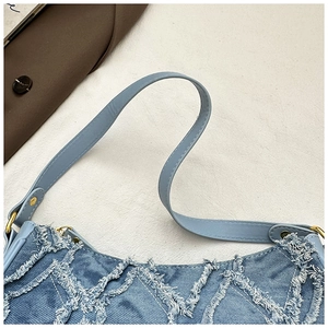 Détail du sac hobo en denim bleu avec texture à franges matelassées et boucle dorée