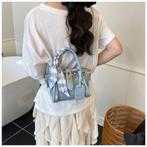 Détail d'un sac seau transparent bleu avec poignée ornée d'un foulard en soie chic