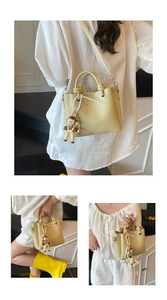 Detalle de bolso cubo amarillo con textura lichi, logo fashion y colgante de muñeca perla