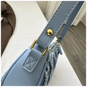 Gros plan détaillé du sac en denim avec rivets dorés, patchwork et bords à franges