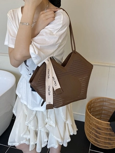 Brown leather tote bag with laser-cut H pattern and silk ribbon shown on a model