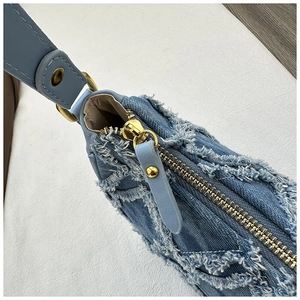 Détail macro de la texture en denim et de la fermeture éclair en métal doré sur le sac