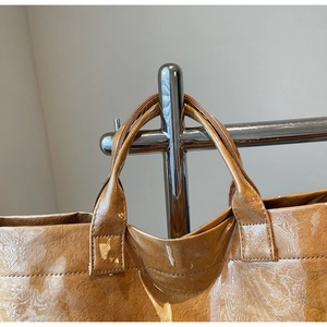 Detail of the reinforced stitching and glossy marble texture on brown tote bag handles