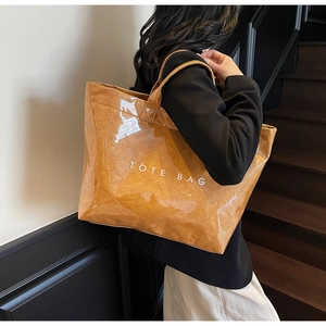Detailed side view of the transparent PVC tote bag with brown inner layer on model