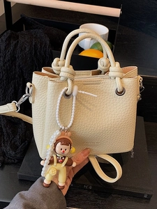 Chic beige bucket bag with litchi grain and unique knot handle with pearl doll charm