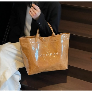 Detail of the brown tote bag featuring glossy waterproof fabric and white printed logo