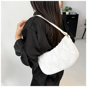 Détail du sac baguette en jean blanc matelassé avec bords effilochés et détails dorés
