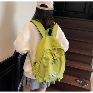Detail of lime green nylon backpack with drawstring pocket and square woven label