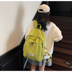 Detail of green canvas backpack featuring a drawstring closure and secure buckle strap