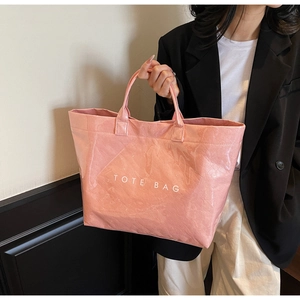 Detail of a large pink waterproof tote bag with shiny crinkle texture and TOTE BAG text