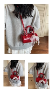 Red cylindrical pillow bag detail with lace bow and pearl charm on a textured finish