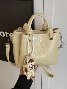 Chic cream leather bucket bag with top handle, fashion print and pearl doll charm