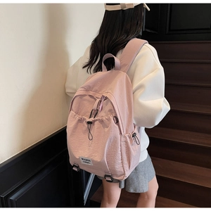 Detailed back view of a light pink nylon backpack with elastic drawstring and side pockets