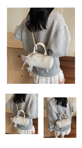 Close-up of white cylinder crossbody bag with lace pearl bow detail and top handles