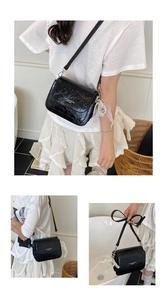 Detail of black glossy wrinkled PU leather crossbody bag with lace pearl charm