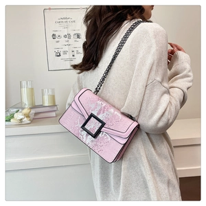 Sac bandoulière rose motif serpent avec boucle noire et chaîne en métal sur modèle