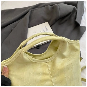 Détail d'un sac à main en cuir vert clair à motif crocodile avec poignées et bandoulière