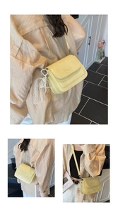 Close-up of yellow wrinkled leather crossbody bag with pearl and lace bow charm
