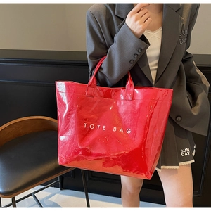 Detailed view of large red glossy patent leather tote bag with white lettering